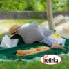 Пролетен пикник на зелена фротирска прекривка со перници, сламени шапки, пијалак и мезе – пролетни зделки од Фротирка.