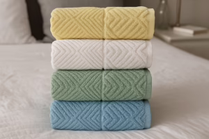 Фротирни пешкири во жолта, бела, зелена и сина боја наредени на кревет – меки, апсорбентни и издржливи, со совети за правилно перење на frotirka.mk.